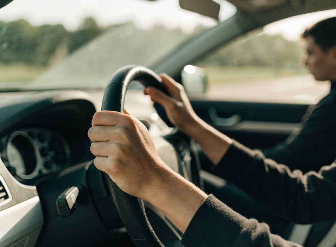 Close-up of a learner's hands on the wheel during a calm in-car driving lesson